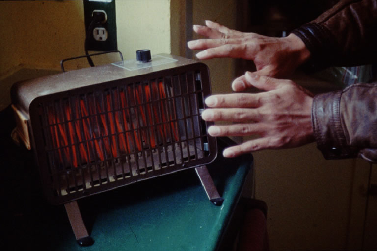 Image of a hand being warmed by a space heater to illustrate infrared radiation.
